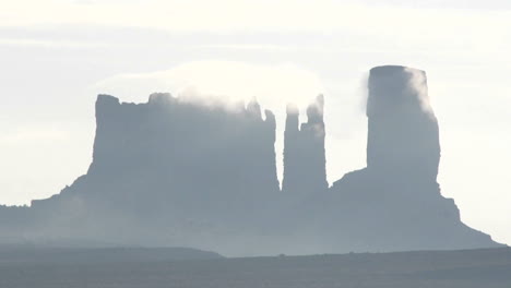 wispy dark clouds move quickly over rock formations in monument valley utah