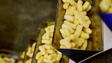 automated process of sweet snacks production at food factory. yellow corn sticks at conveyor belt. close up.