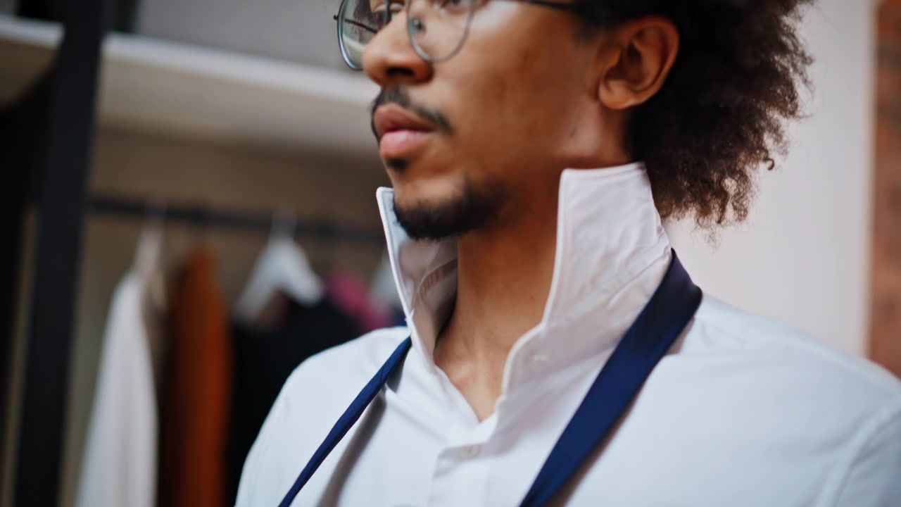 Close up hands buttoning shirt cuff. African american man dressing tie wardrobe.