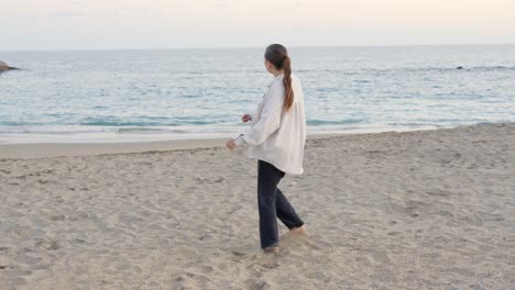 woman dancing alone barefoot on sand, practising next to shore, slowmo