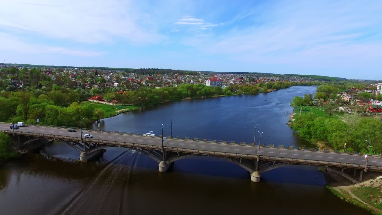 Motor boat sliding by the river and under the large bridge. Beautiful city scenery from top view.