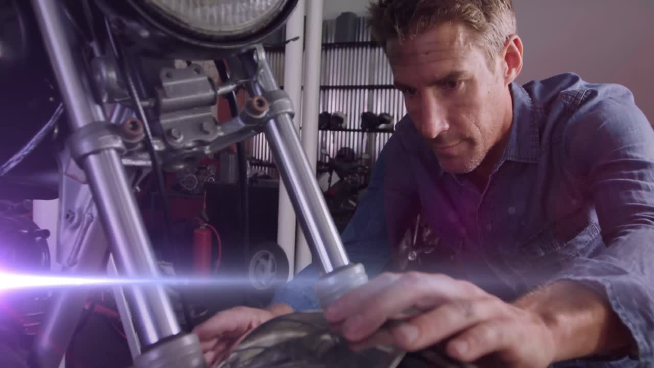 animación de luces brillantes sobre un mecánico caucásico reparando una motocicleta en un garaje