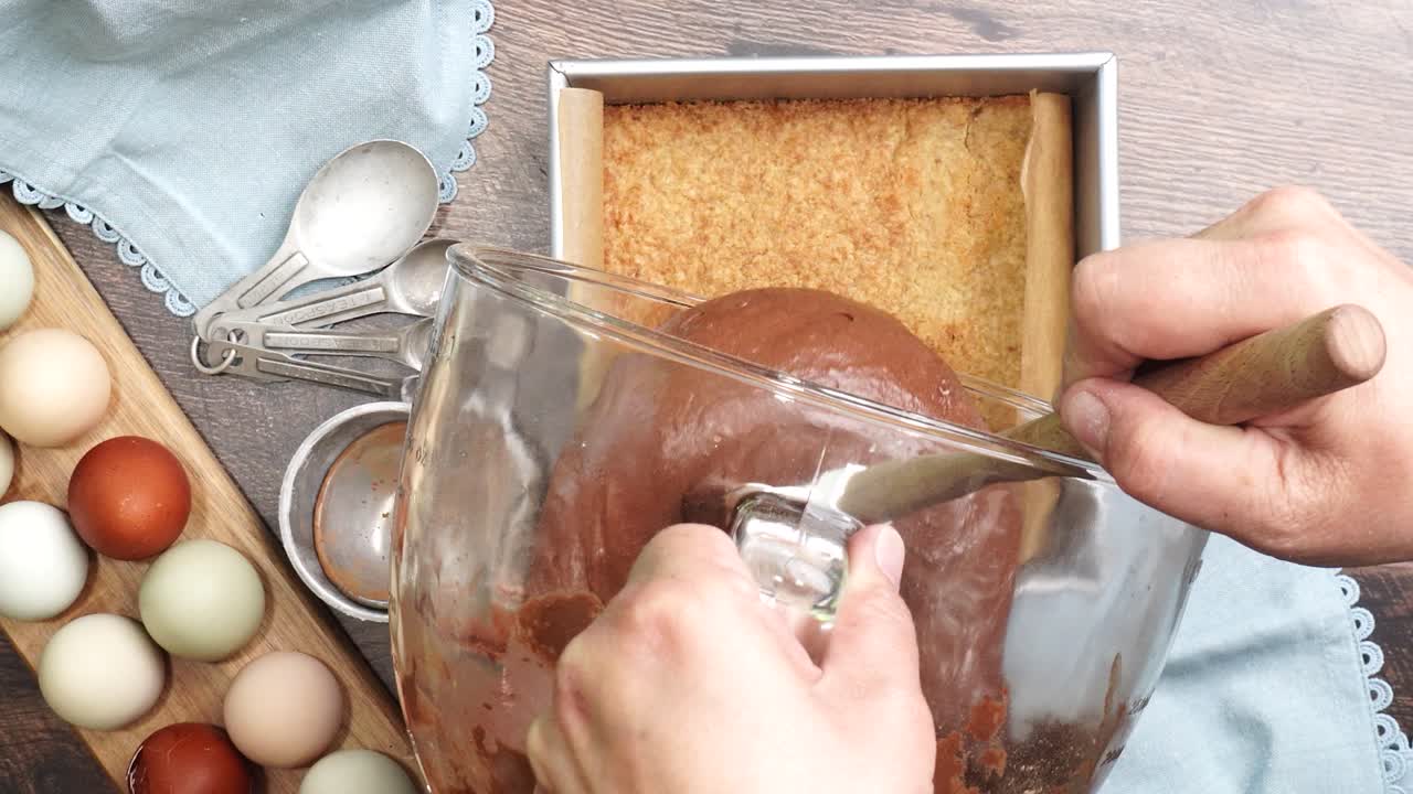 Baking delicious caramel pecan brownies. Pouring the brownie batter into the square baking pan. Freshly baked gooey chocolate brownies with sweet caramel and nutty pecans.