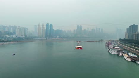 aerial view following a cable car cabin above the river in chongqing, china, showcasing the city’s skyline and the stunning landscape from a unique perspective during daytime.