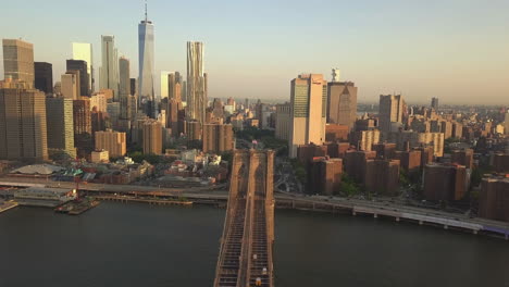 AERIAL:-Flight-over-Brooklyn-Bridge-with-view-over-Manhattan-New-York-City-Skyline-at-Sunset-in-beautiful