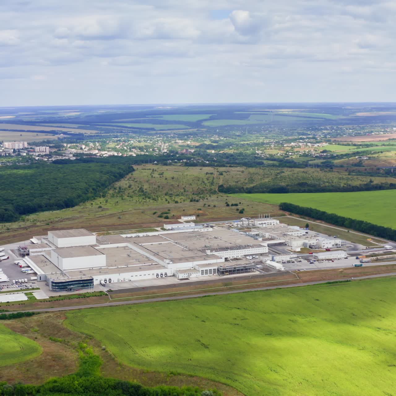 Panoramic view of industry in nature. Modern manufacturing plant surrounded by green fields in the countryside. View from the air