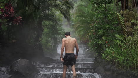 Man-walks-up-beautiful-waterfall-hot-springs-rain-forest-Costa-Rica,-slow-motion
