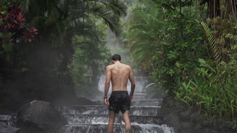 man walks up beautiful waterfall hot springs rain forest costa rica, slow motion