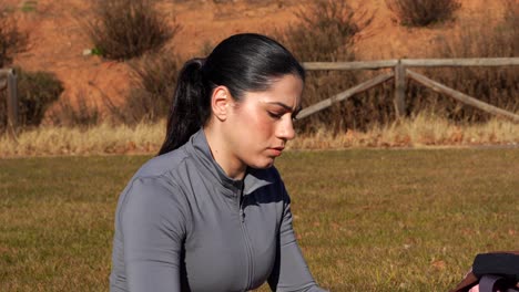 mujer usando un rodillo de espuma para los músculos de las piernas durante el ejercicio en un parque