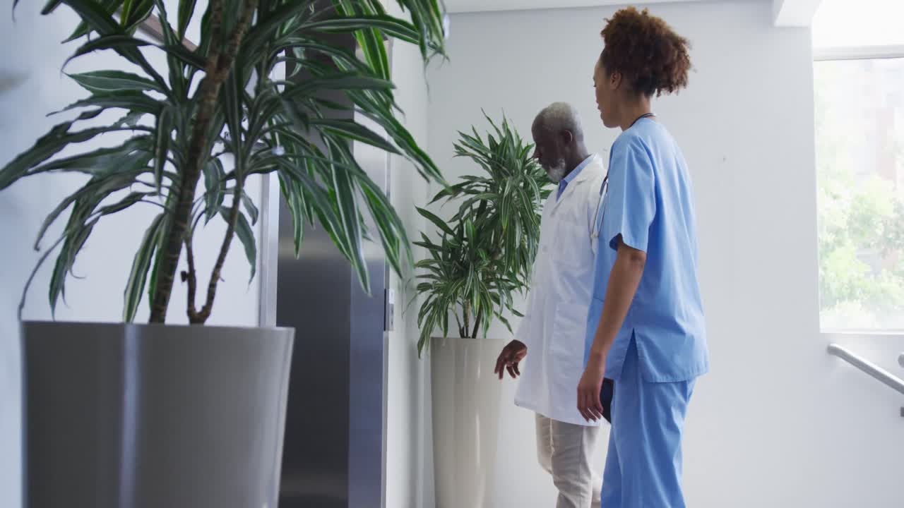 Médicos e médicas de diversas etnias de pé no hospital, esperando o elevador.