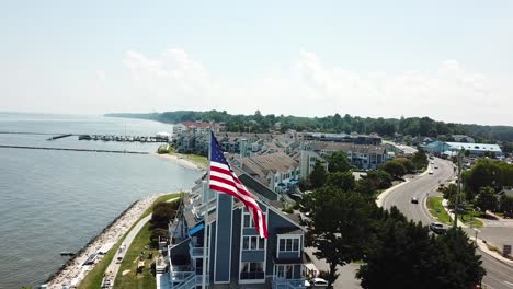 aerial view on american flag waving on pole on coast of chesapeake bay, maryland usa