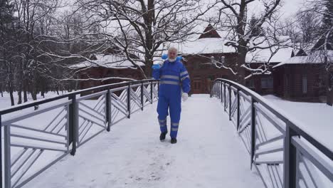 old cleaner walking with shovel on shoulder.