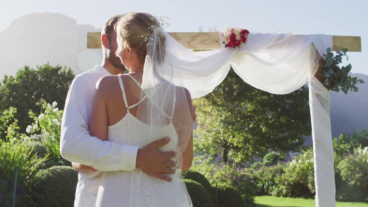 Portrait of happy caucasian newly wed couple, dancing in front of altar outdoors