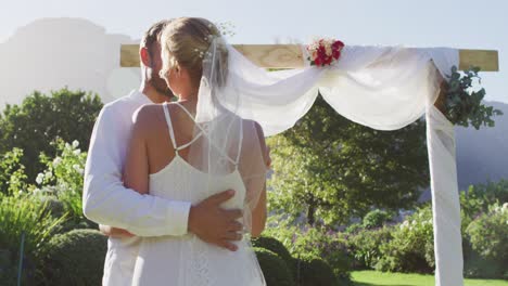 Portrait-of-happy-caucasian-newly-wed-couple,-dancing-in-front-of-altar-outdoors