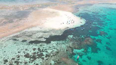 aerial view of a tropical sandbar with boats and swimmers