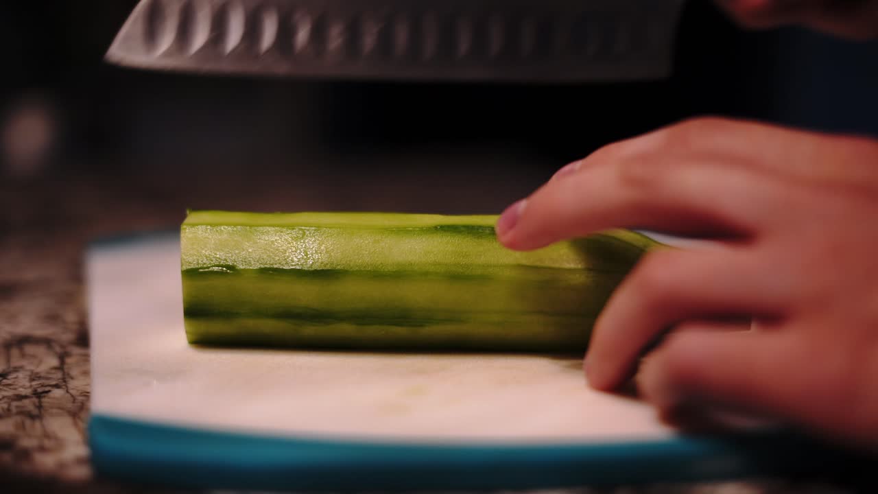 Cutting healthy cucumber splitting across in half into two, home kitchen