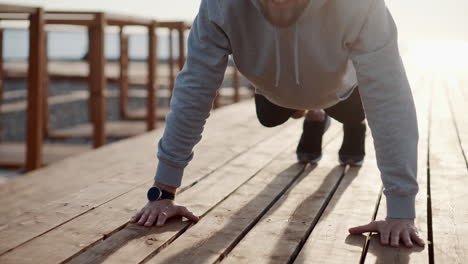 man doing push-ups on a wooden boardwalk at the beach