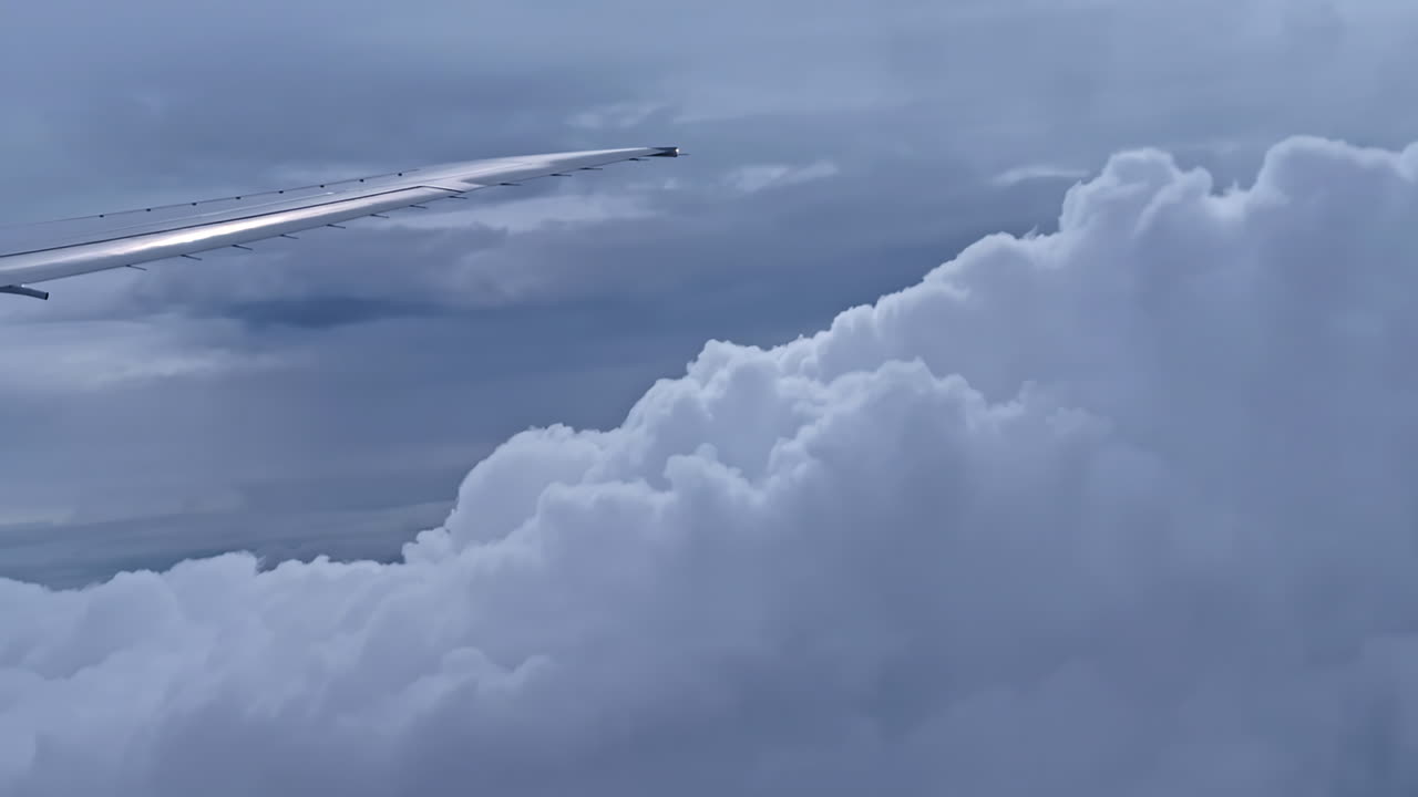 Plane wing window view POV airplane travelling over layer of clouds, high altitude