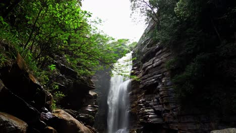 Beautiful-4K-tilting-down-shot-of-the-beautiful-Mosquito-waterfall-from-behind-foliage-and-a-cliff-in-the-Chapada-Diamantina-National-Park-in-the-Northeastern-State-of-Brazil-Bahia