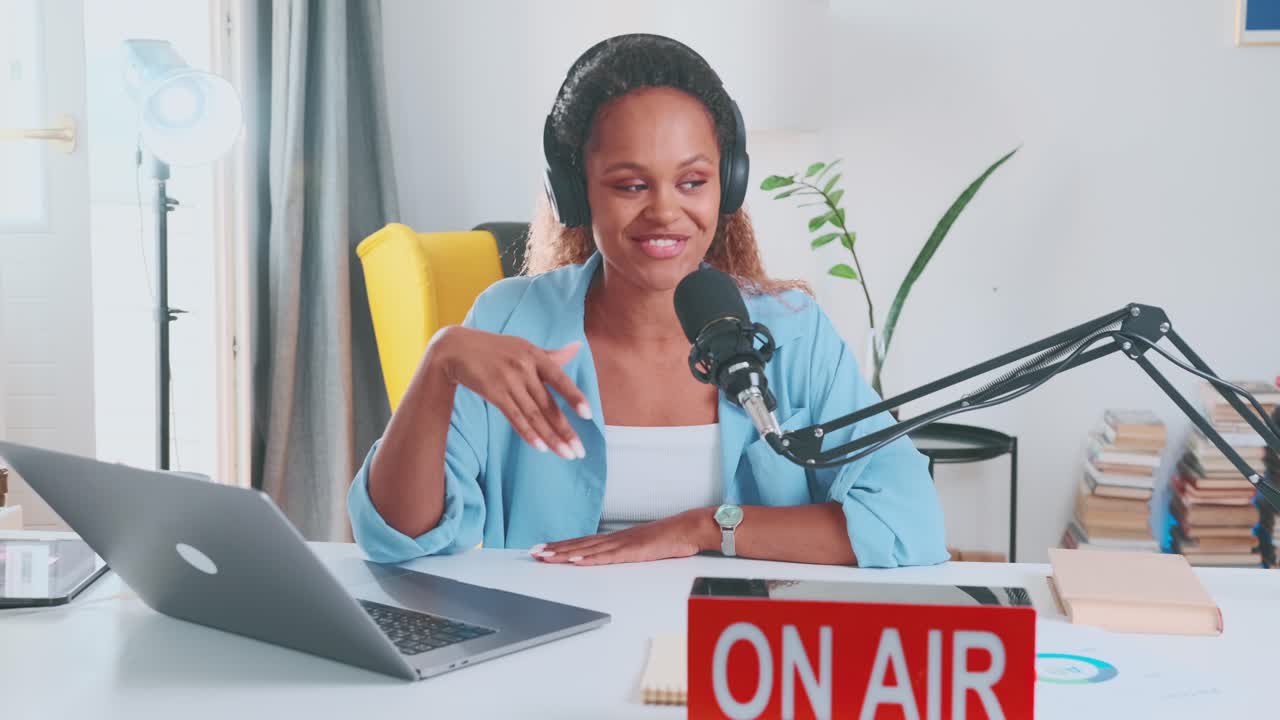 Young african american woman radio presenter sings on air sits near microphone