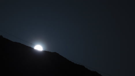 the full moon rising behind mountain ridge with beautiful glowing light