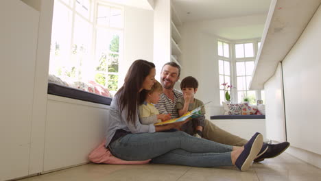 familia sentada en el suelo leyendo una historia en casa filmada en r3d