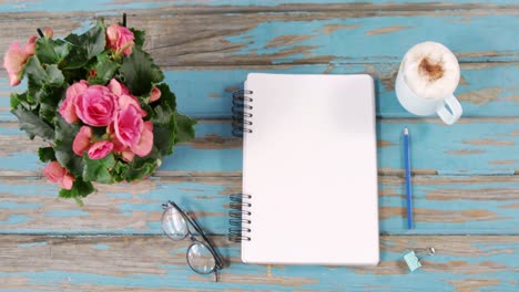 pink flowers, cup of coffee, diary, binder clip and spectacles