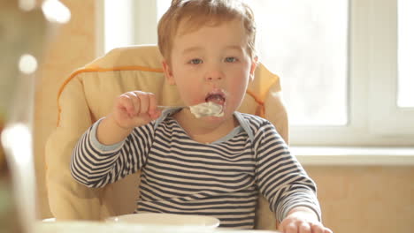 little boy eats porridge in the morning