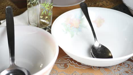 empty white bowl with spoon and other dishes on a table