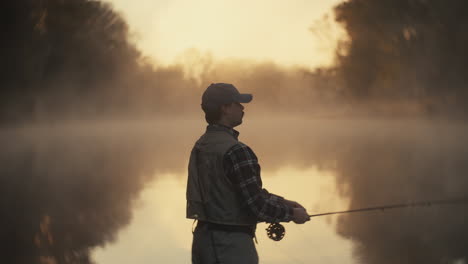 fisherman fly fishing in a misty morning sunrise