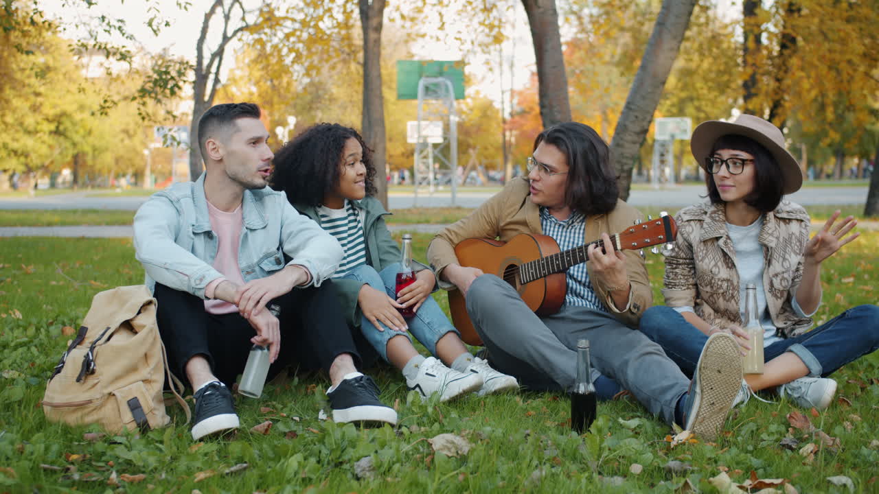 Friends playing guitar in the park