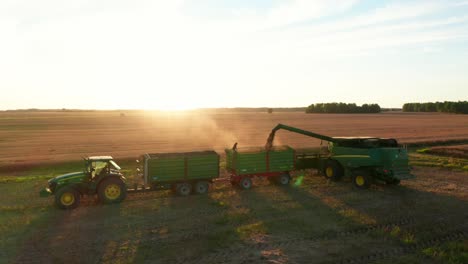 máquinas agrícolas trabajando en el campo, vertiendo cultivos en el maletero, mientras la persona observa