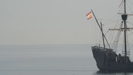 ferdinand magellan nao victoria carrack boat replica sails in the mediterranean at sunrise in calm sea side shot exiting the frame in slow motion 60fps