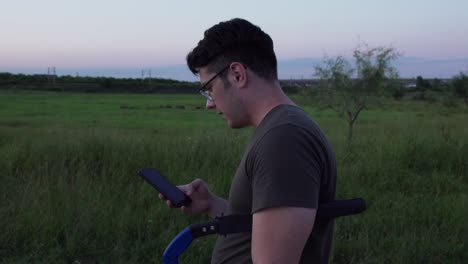 side view of a european man talking on the phone while walking in the meadow at dusk