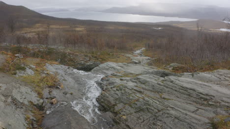 Water-flows-between-rocks-towards-lake-in-29,97fps