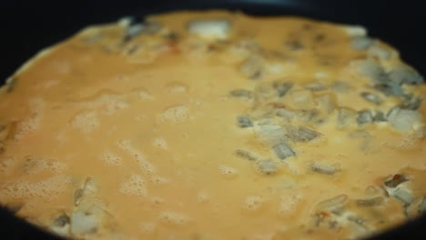 A-time-lapse-close-up-shot,-egg-mixture-filling-the-grilled-ognion,-turning-over-the-omlet-on-a-black-hot-pan-and-scrumbling-the-eggs,-making-a-breakfast-4K-video