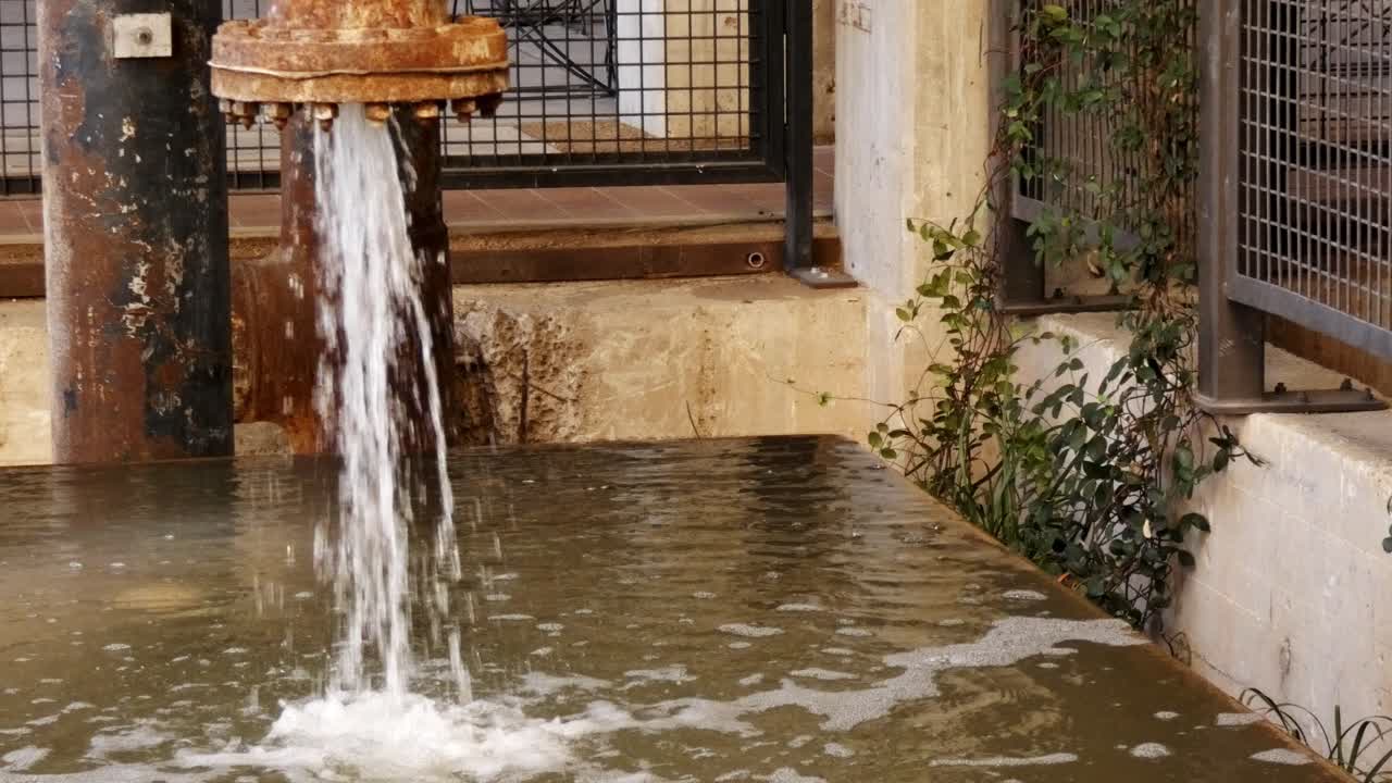 el agua sale a borbotones de la vieja tubería oxidada al tanque de agua para el mantenimiento