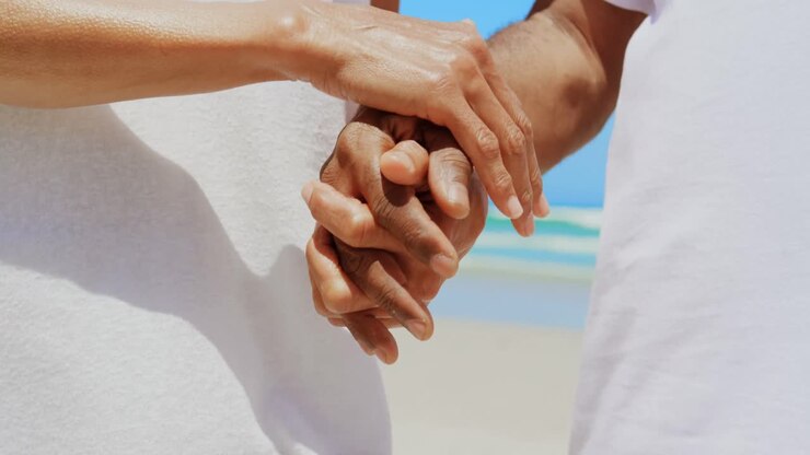 Plan moyen d'un couple senior afro-américain romantique et actif se tenant la main sur la plage 4k