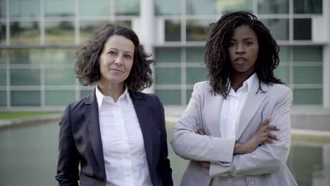 confident workers standing near building and looking at camera