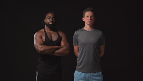 close up studio portrait of determined male athletes training in fitness clothing shot against black background