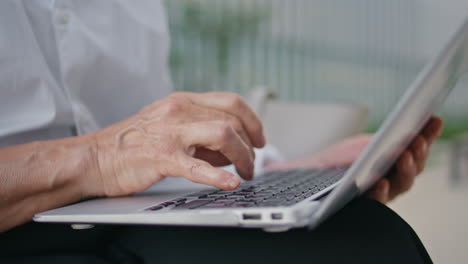 manos de anciana escribiendo en el teclado de la computadora portátil de cerca. dama madura desconocida escribiendo texto