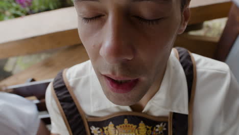 man drinking beer in traditional bavarian clothing