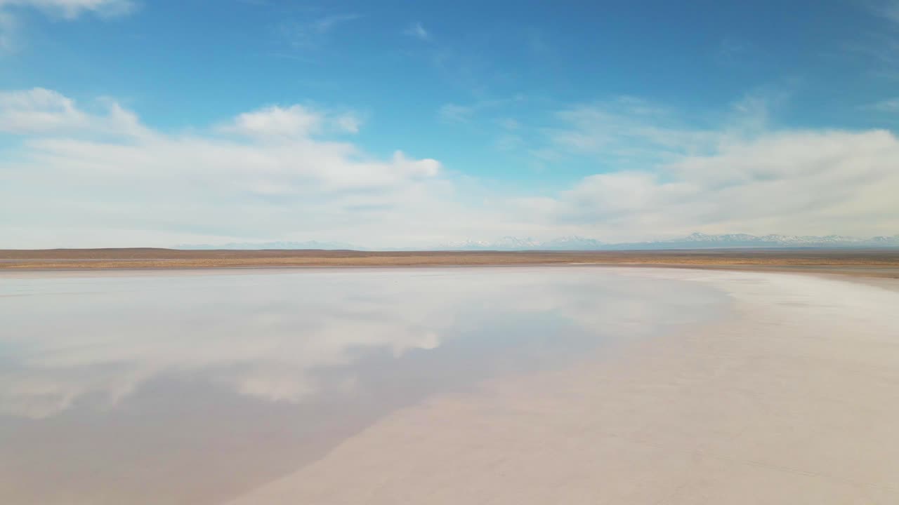 una laguna de agua salada que refleja el cielo con las montañas de los andes en el fondo