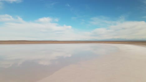 a saltwater lagoon reflecting the sky with the andes mountains in the background