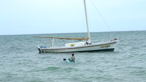 An-old-man-on-the-kayak-approaching-to-a-boat-in-the-ocean-in-Belize