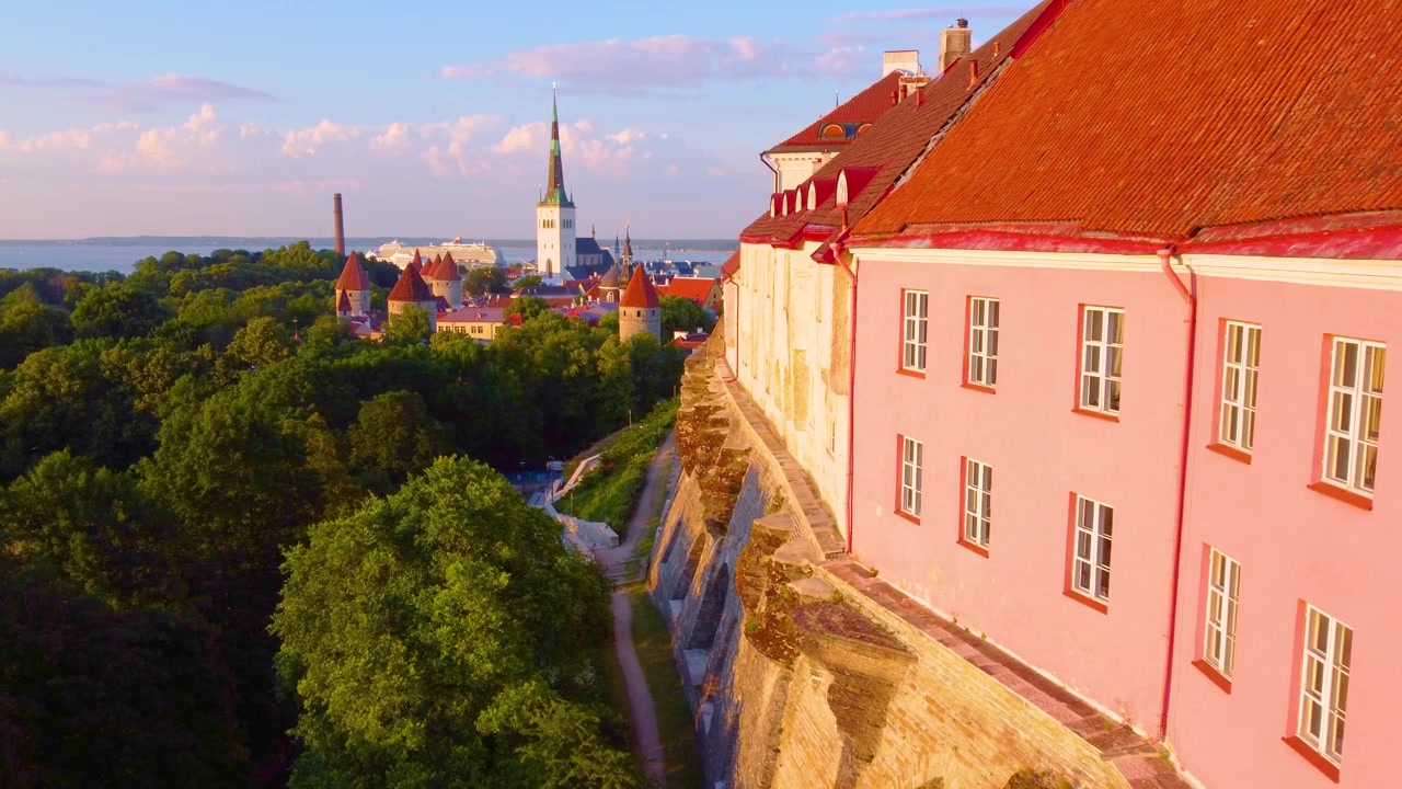 Edificios con tejados rojos dominan exuberantes árboles verdes y el horizonte de Tallin al atardecer en Estonia.