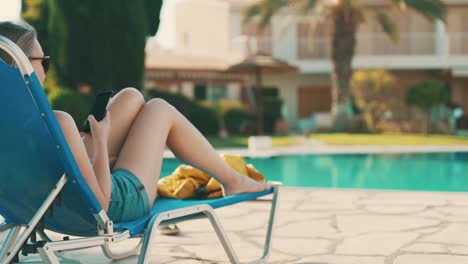 woman with smartphone near the swimming pool.