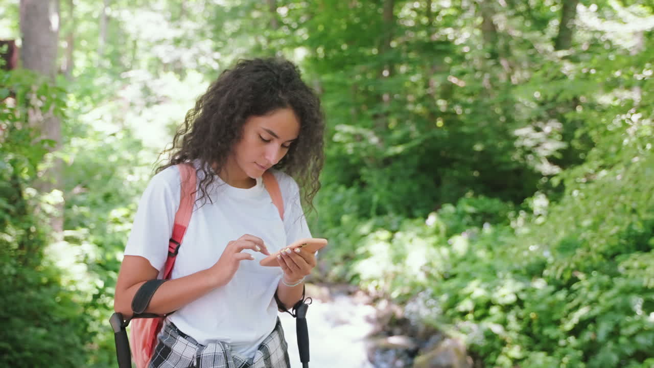 mujer caminando en el bosque usando el teléfono