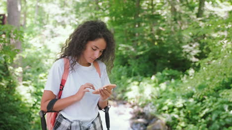 mujer caminando en el bosque usando el teléfono