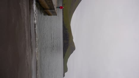 Mujer-Reflexionando-Sobre-El-Paisaje-Feroés,-Mirando-El-Océano-Atlántico-Desde-El-Muelle-De-Bour-En-Vagar